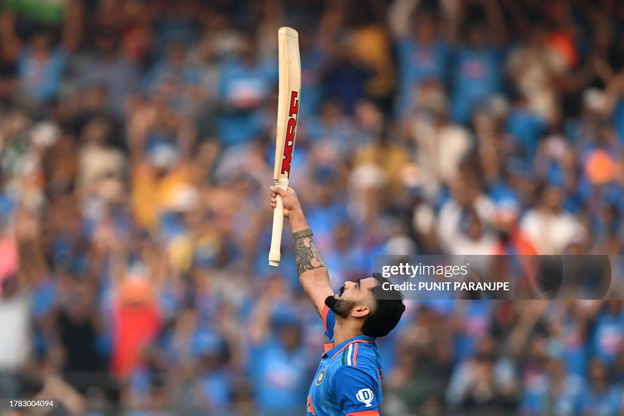 Virat Kohli looking up with MRF bat raised vertically in celebration after scoring his 50th ODI century at Wankhede Stadium